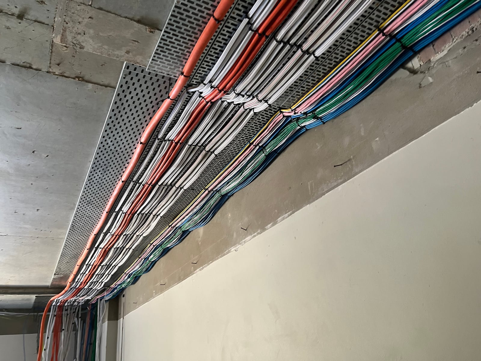Commercial fit-out with power and data cabling bundled along a perforated cable tray